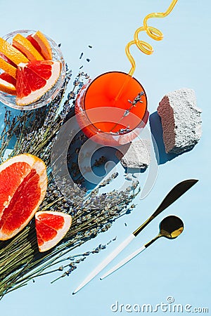 Grapefruit, orange juice, lavender, rock. Modern vegetarian breakfast on blue. Trendy minimal flat lay Stock Photo