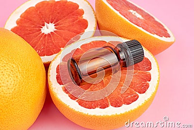 Grapefruit pure essential oil with fresh grapefruit halves on pink background. Stock Photo
