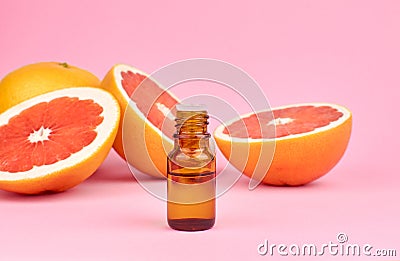 Grapefruit pure essential oil with fresh grapefruit halves on pink background Stock Photo