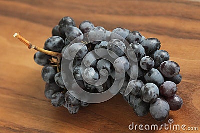 Grapes. A bunch of dark, black grapes lies on a wooden board close-up Stock Photo