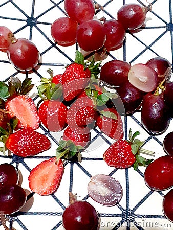 Grapes and strawberries are scattered on a black and white polygon background Stock Photo