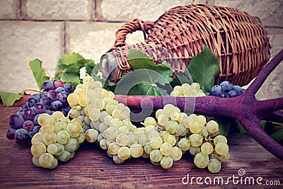 Grapes and vintage wicker bottle on the wooden table Stock Photo