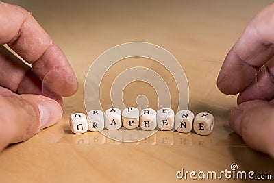 Graphene word in wooden letters and mans`s hands with a transparent and flexible foil Stock Photo