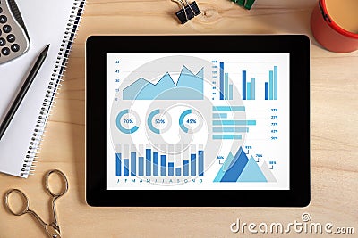 Graphs and charts elements on tablet screen with office objects Stock Photo