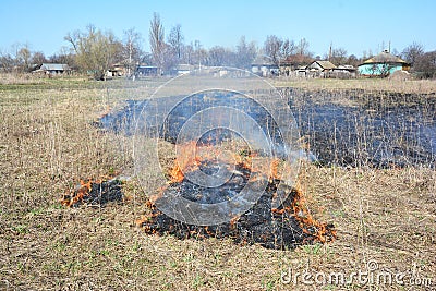 Grass burning near village houses. Burning grass releases more nitrogen pollution than burning wood Stock Photo