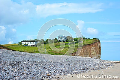 Grass covered cliff with buildings at beach at Saint-Aubin-sur-Mer in Normandy France Stock Photo