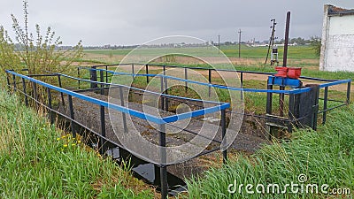 On the grassy bank of the reservoir, a concrete hydraulic structure was built with a damper on a worm mechanism to regulate the wa Stock Photo