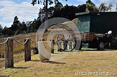 A grassy yard with corn husk basket and a cart wheel in the countryside Stock Photo