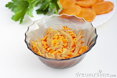 Grated carrots in a bowl, peeled and cut into pieces carrots, parsley Stock Photo