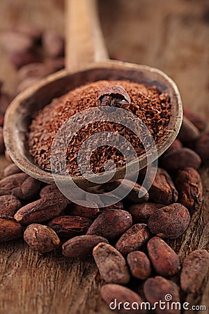 grated dark chocolate in old wooden spoon on roasted cocoa chocolate beans background Stock Photo