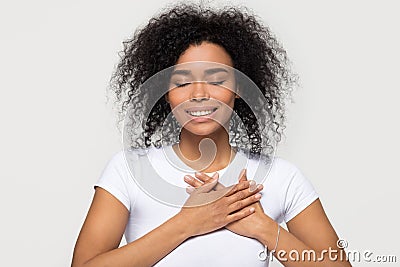 Grateful happy black woman holding hands on chest feeling thankful Stock Photo