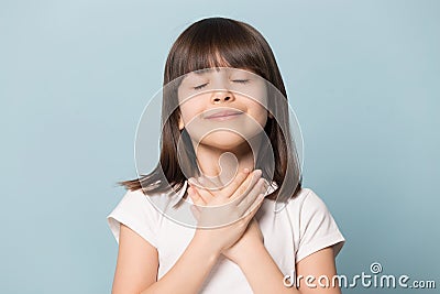 Grateful little girl closed eyes hold hand on chest Stock Photo