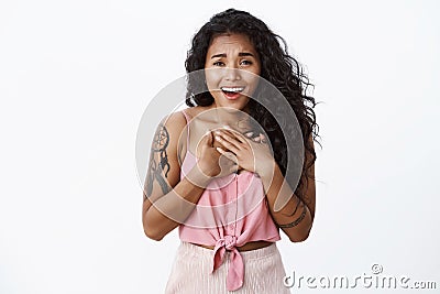 Grateful and pleased good-looking african american curly-haired girl press hands to chest thankful, sighing delighted Stock Photo