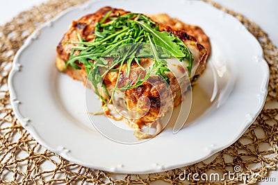 Gratin lasagne with fresh rucola leaf on white plate Stock Photo