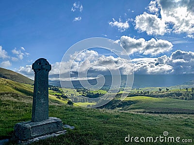 Grave with the Celtic cross monument in the field under a blu sky Editorial Stock Photo