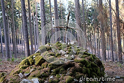 A grave mound made of stones covered with green moss, wooden cross at top, an unknown old grave for pilot who died in Taunus Stock Photo