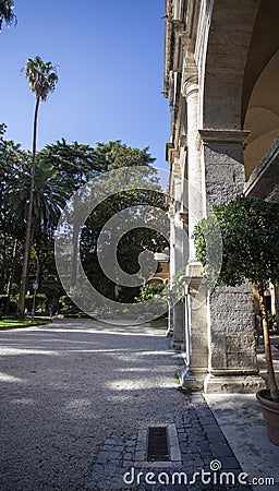 A gravel courtyard in Rome with palm trees and columns Stock Photo