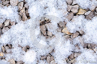 Gravel with snowflakes texture. Small stones, little rocks, pebbles in many shades of grey partially covered with snow. Stock Photo