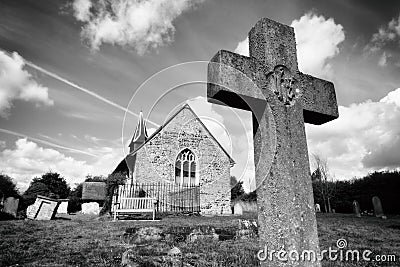 Gravestone Cross and Church in a Graveyard Stock Photo