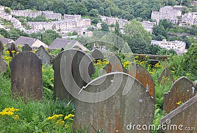 Gravestones overgrown with weeds overlooking the town of hebden bridge at the disused cross lanes former methodist burial ground Stock Photo