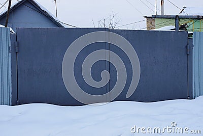 Gray closed metal gates in snowdrifts of white snow Stock Photo