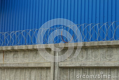 Gray concrete fence with iron barbed wire Stock Photo