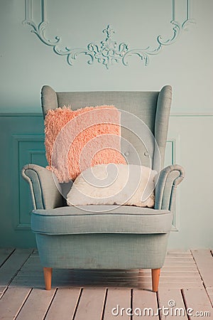 Gray easy armchair with pink scarf, pillow and book next to bed Stock Photo