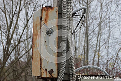 A gray metal box in brown rust and with electric wires Stock Photo