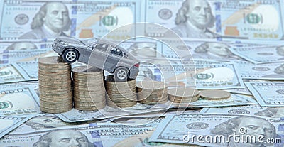 A gray model of a car with coins in the form of a histogram on a dollars background. Concept of lending, savings, insurance Stock Photo