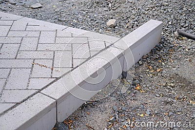 gray paving blocks on the ballast, side view, construction site of pavement modern granite cobblestone road in city center, Stock Photo