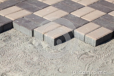 Gray paving blocks - side view. New sidewalk with rectangular stones. Paving tiles in the process of laying Stock Photo