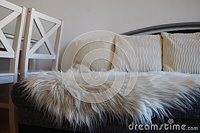 Gray sofa with boucle upholstery fabric and white decorative fluted cushions. White rug or bedspread made of faux fur Stock Photo