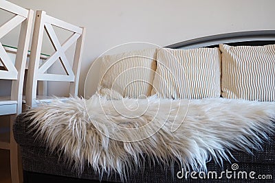 Gray sofa with boucle upholstery fabric and white decorative fluted cushions. White rug or bedspread made of faux fur Stock Photo