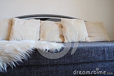 Gray sofa with rough upholstery fabric boucle and white decorative fluted cushions. A long pile white faux fur rug or Stock Photo