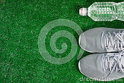 Gray Sports Running Shoes and bottle of water on green grass. Stock Photo