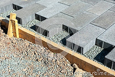 Gray stone pavers installation. Pavers installed in a running bond pattern on a gravel base next to wooden formwork Stock Photo