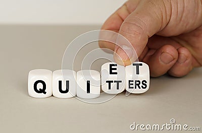 On a gray surface are white cubes with the inscription - quiet or quitters Stock Photo