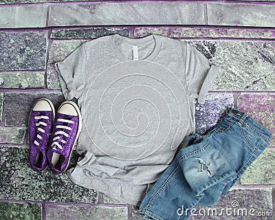 Gray T Shirt mockup flat lay on purple brick background with purple shoes and ripped jeans Stock Photo