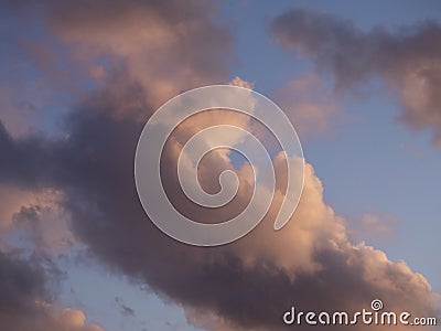 Gray-white thundercloud in a blue sky. Pink sky background at sunset Stock Photo