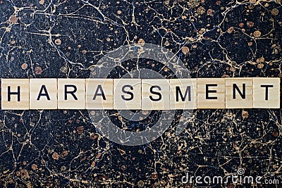 Gray word harassment from wooden letters in black font Stock Photo