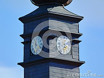 Gray zink covered clock tower. white clock face. golden clock hands Stock Photo