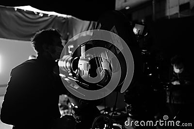 Grayscale of a cameraman in a mask near the camera Stock Photo