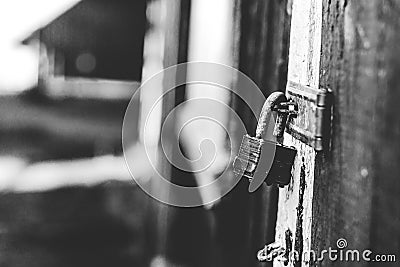 Grayscale closeup of a lock hanging from the door. Stock Photo