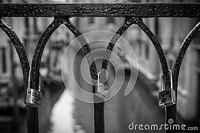 Grayscale closeup of the love locks on a rusty bridge railing. Venice, Italy. Editorial Stock Photo