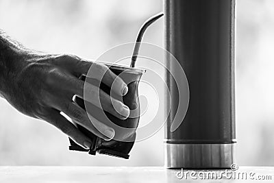 Grayscale selective focus shot of a hand holding calabash mate cup with straw Stock Photo