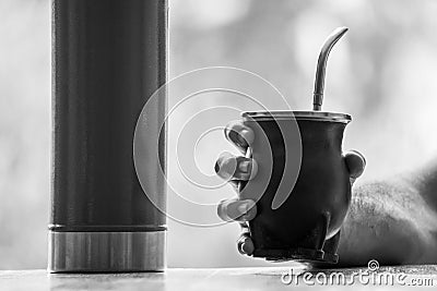 Grayscale selective focus shot of a hand holding a calabash mate cup with straw Stock Photo