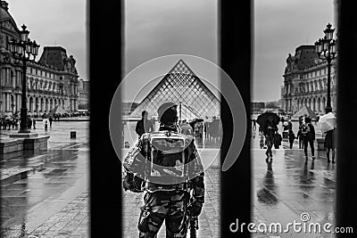 Grayscale shot of the back of the guardian in front of the pyramid of Louvre Museum in Paris Editorial Stock Photo