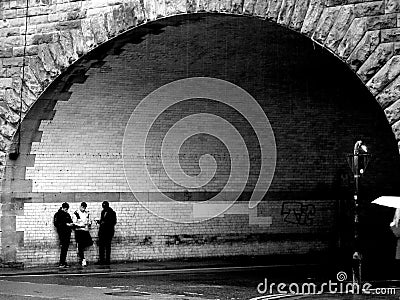 Grayscale shot of group of young boys hanging out by the entrance of arch tunnel Editorial Stock Photo