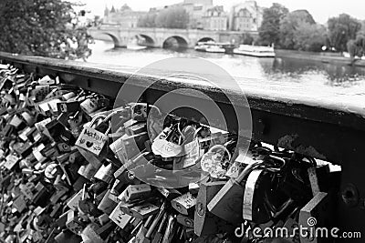 Grayscale shot of the padlocks of love on a Seine river bridge fence in Paris Editorial Stock Photo