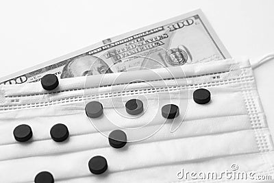 Grayscale shot of pills on a surgical mask on a dollar banknote Stock Photo